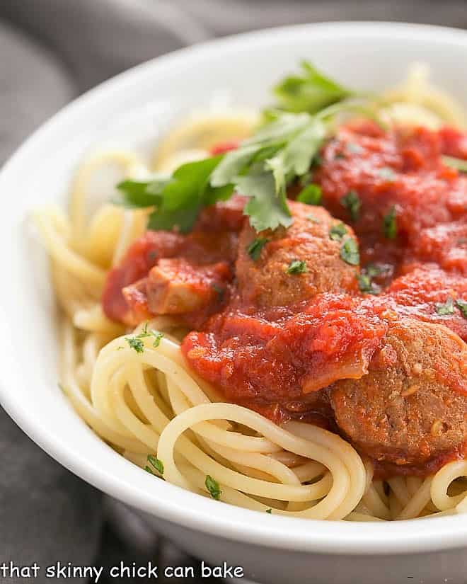 Close view of homemade pasta sauce with sausage in a white bowl with spaghetti 