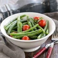 Italian Sauteed Green Beans in a white ceramic bowl with two red handled forks