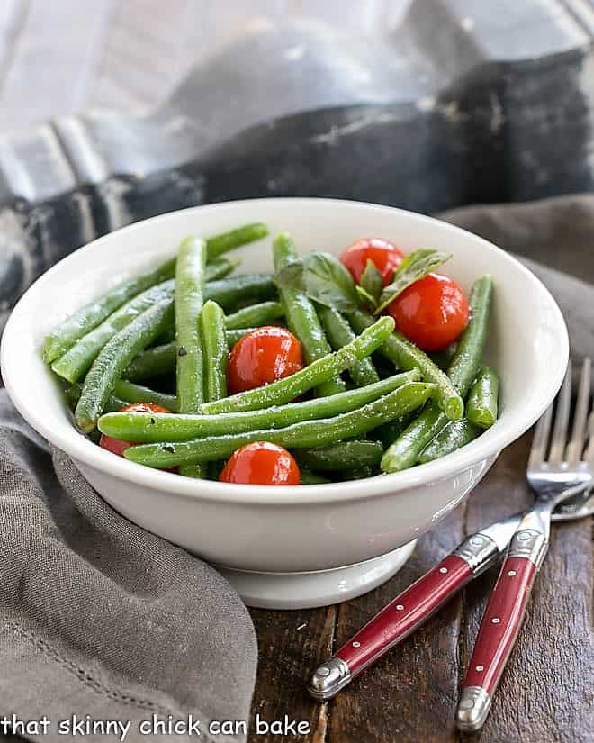 Italian Sauteed Green Beans in a white ceramic bowl with two red handled forks