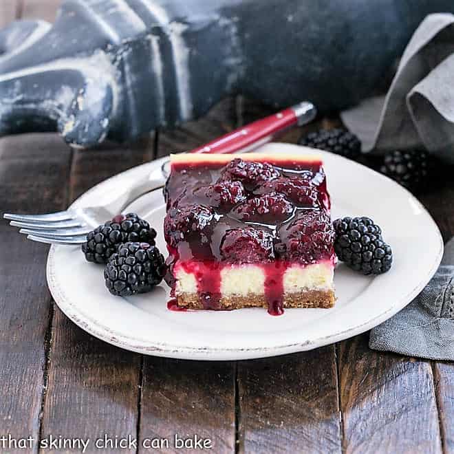 Black berry Topped cheesecake bar with fresh blackberries on a round white plate