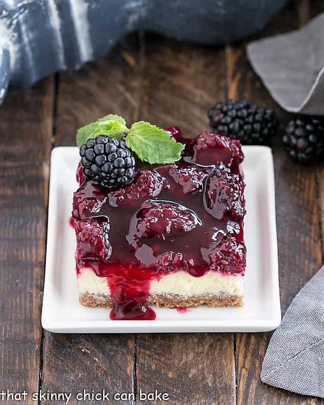 Cheesecake Bar with Berry Topping on a square white plate with a sprig of mint.