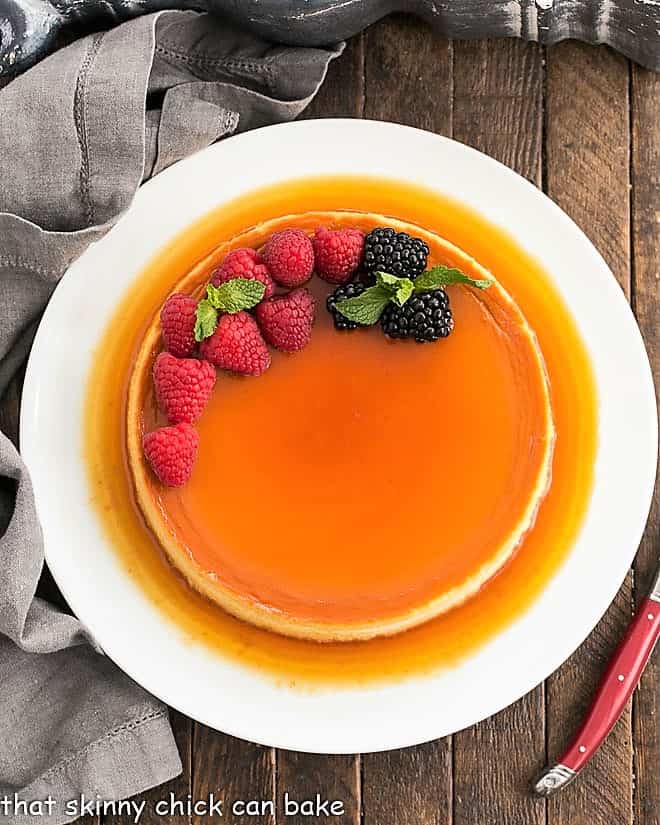 This rich and dreamy leche Flan is a cross between creme brulee and cheesecake! Everyone will want to lick their plates clean! Overhead view of Cream Cheese Flan on a white serving plate.
