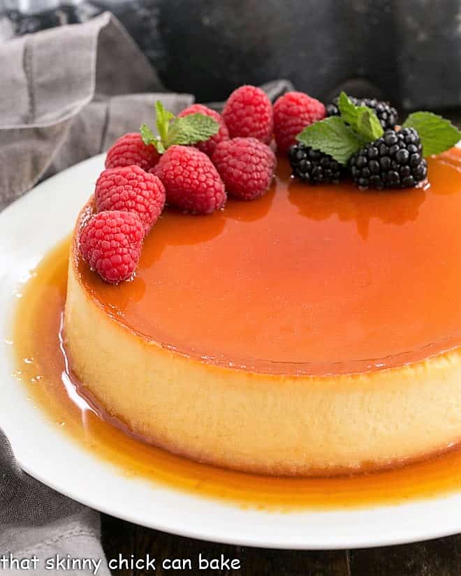 Flan Recipe topped with berries on a white plate.
