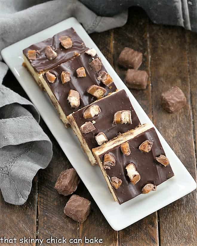 Twix Cheesecake Bars on a white ceramic platter