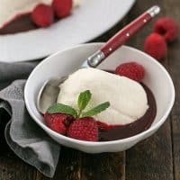 Coeur a la Creme in a white bowl with raspberries and mint to garnish