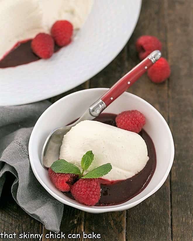 Serving of no bake cheesecake in a bowl with fresh raspberries and mint.