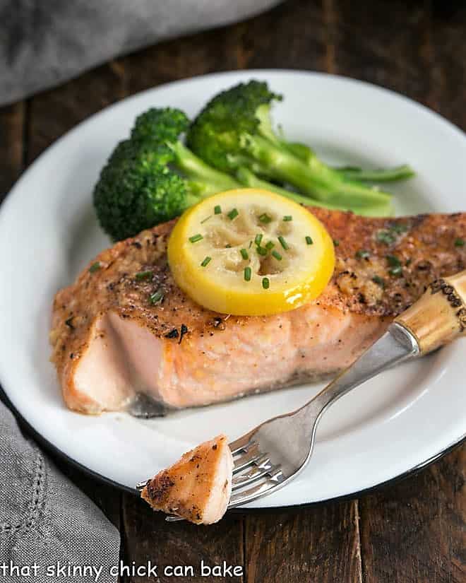 Roasted Salmon on a white plate with broccoli with a forkful removed.