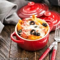 Cheesy Pasta Bake in a red crock with two forks