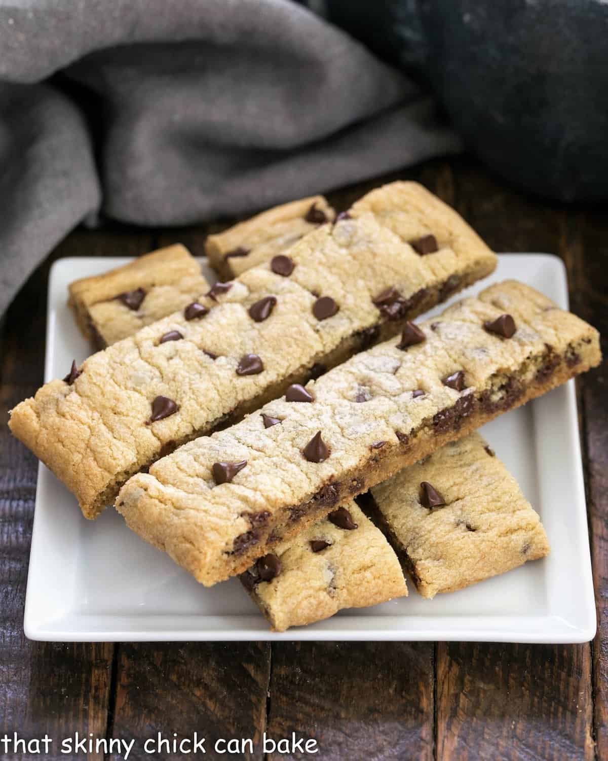 4 chocolate chip cookie sticks on a square white plate.