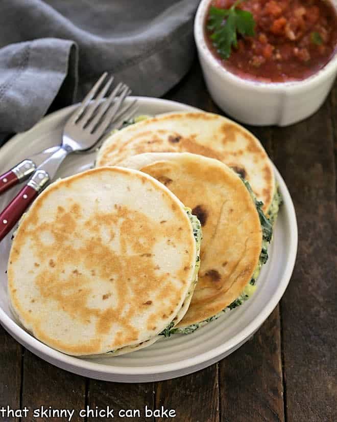 3 quesadillas on a white plate with 2 red handled forks.