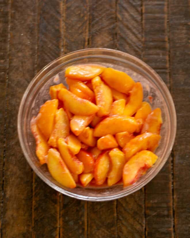 Sliced peaches with dry ingredients and lemon juice in bowl