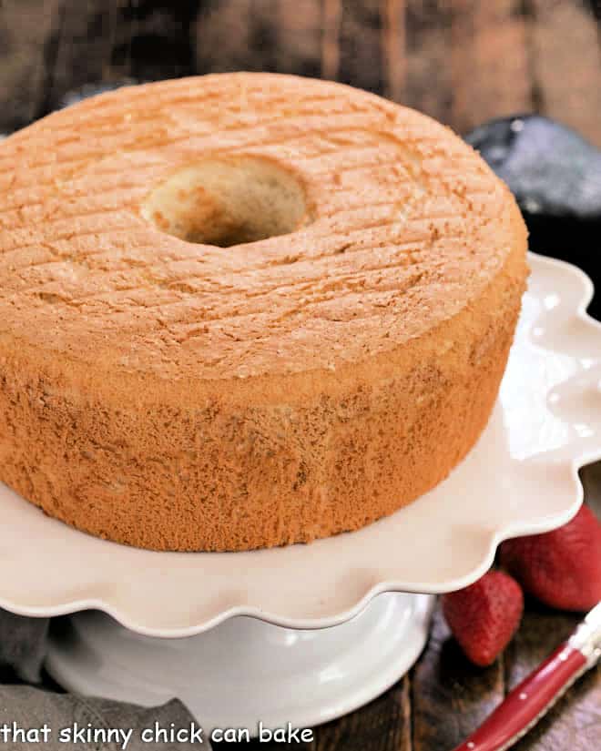 Whole angel food cake on a white cake stand.