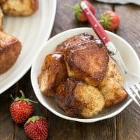 Homemade monkey bread in a small white bowl with a fork and a few small strawwberries