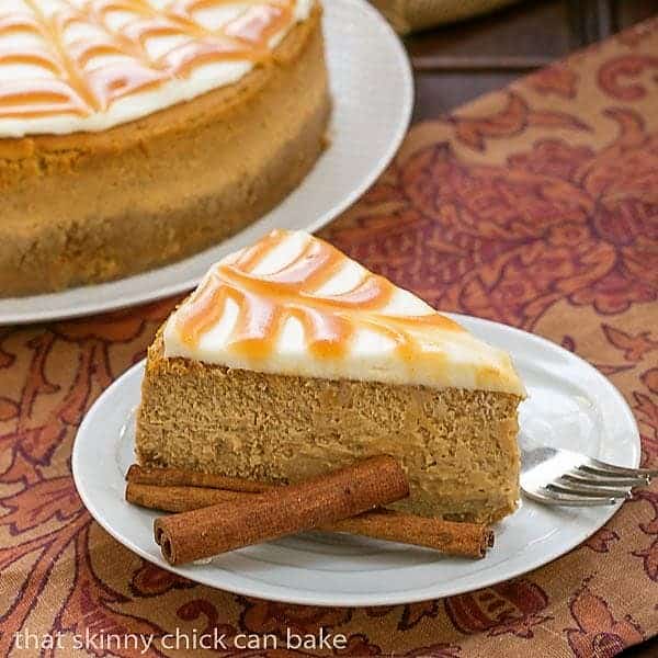 Caramel Topped Pumpkin Cheesecake slice on a white plate with cinnamon sticks