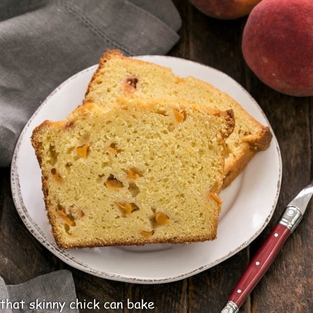 Overhead view of 2 slices of peach cake on a white plate with a red handled fork