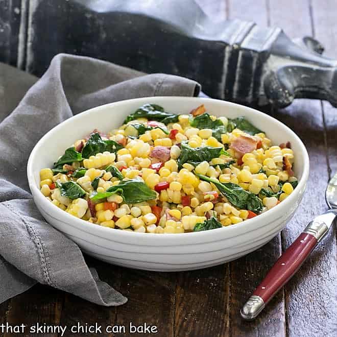 Skillet corn recipe in a white serving dish with a red handle spoon