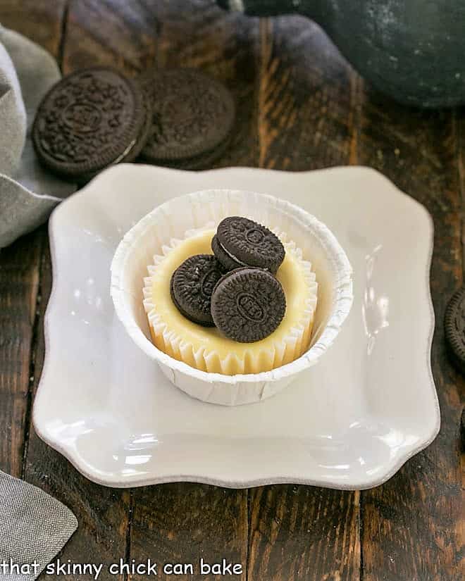 One Oreo cheesecake topped with 3 mini oreos on a square white plate.