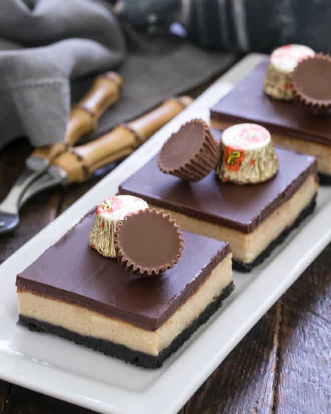 Side view of 3 cheesecake bars on a white tray