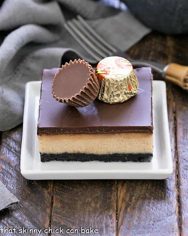 Layered peanut butter cheesecake bar topped with 2 mini peanut butter cups.