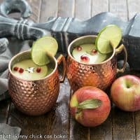 2 apple cider mules in copper mugs with 2 apples