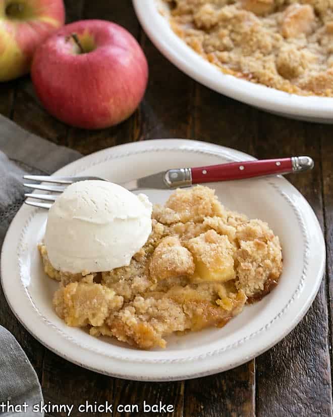 Apple crumble with a scoop of ice cream on a white dessert plate.