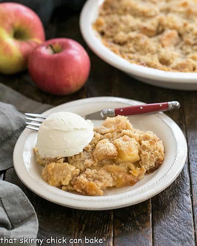 Serving of apple crumble with a scoop of ice cream on a white plate