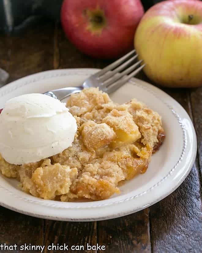 Apple crumble on a white plate with a scoop of ice cream.
