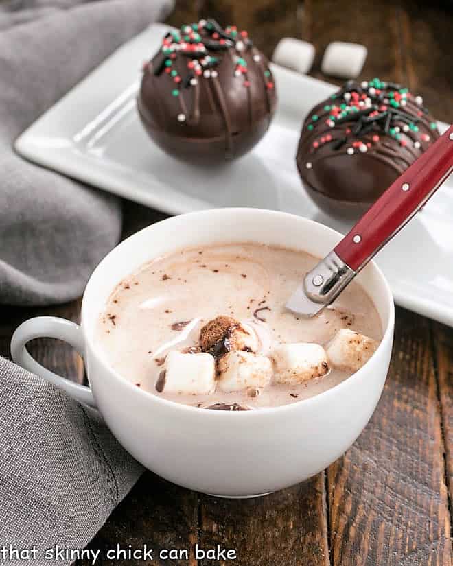 Hot Cocoa Recipe in a white tea cup with a red handle spoon.