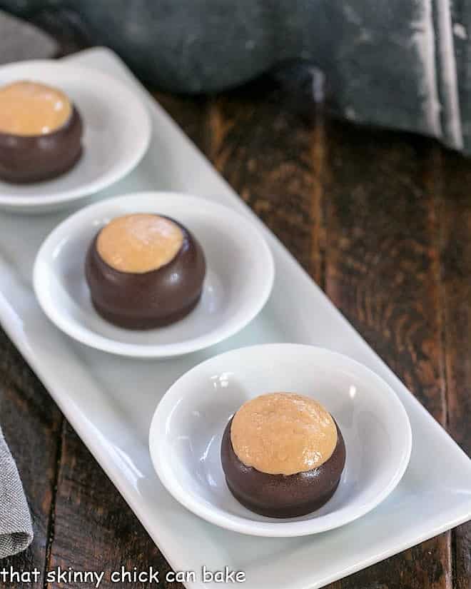 3 peanut butter balls in white bowls on a white tray
