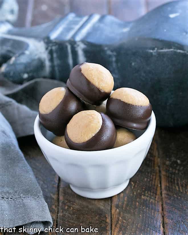 The BEST Peanut Butter Balls - AKA Buckeyes are an easy confection with only 6 ingredients! Reeses lovers will go crazy for this Buckeye Recipe! Peanut Butter Balls in a white bowl.