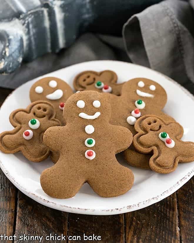 Different sized gingerbread man cookies on a round white plate.