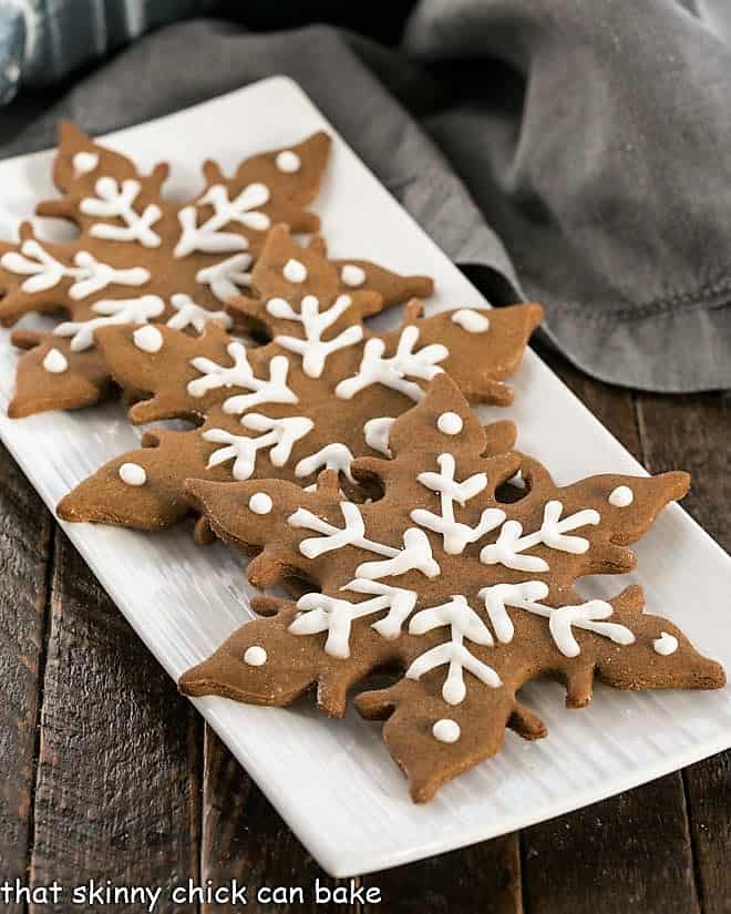 3 gingergread snowflakes on a white platter.