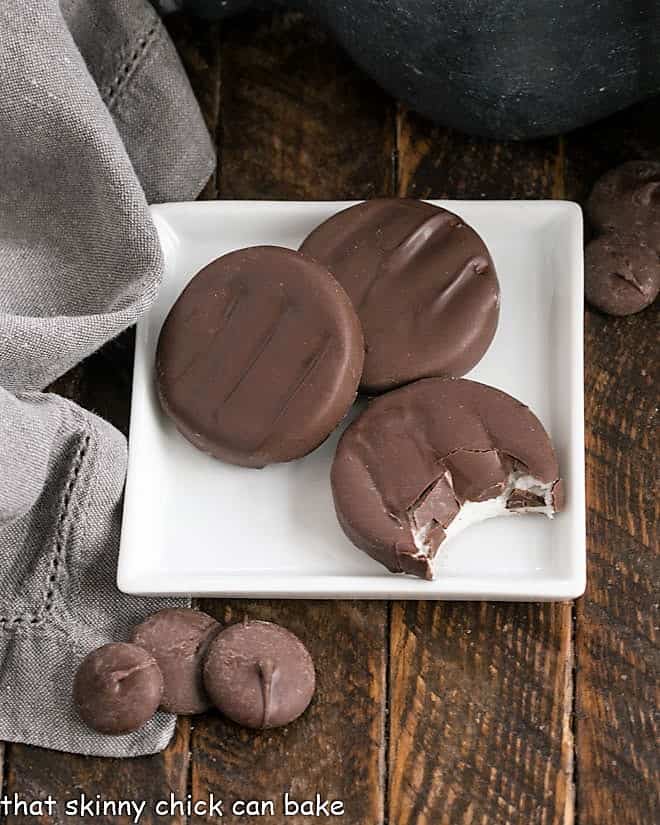 Overhead view of 3 peppermint pattties on a square white plate.