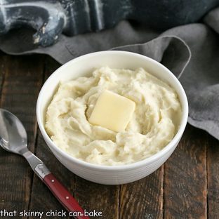 Bowl of cream cheese mashed potatoes in a white bowl with a pat of butter