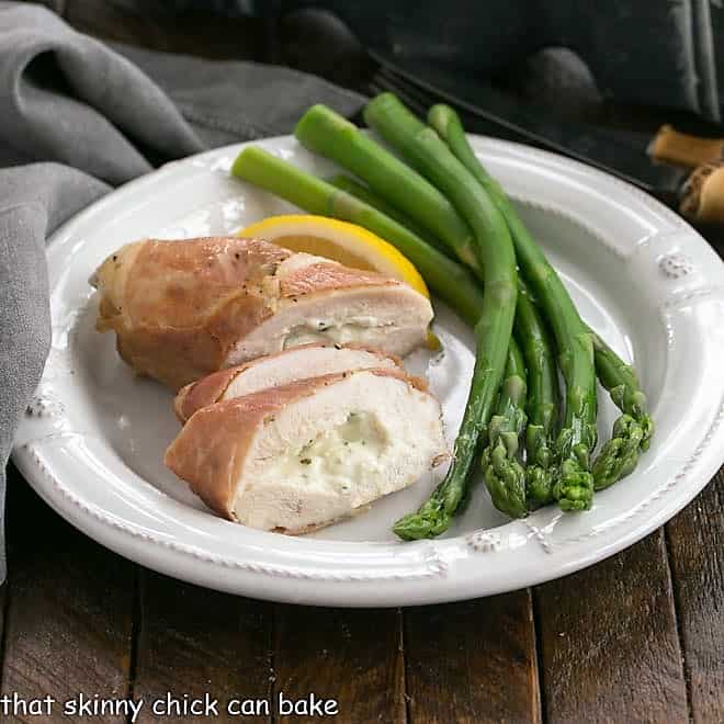 Bousin chicken breast sliced on a white plate with aspargus spears