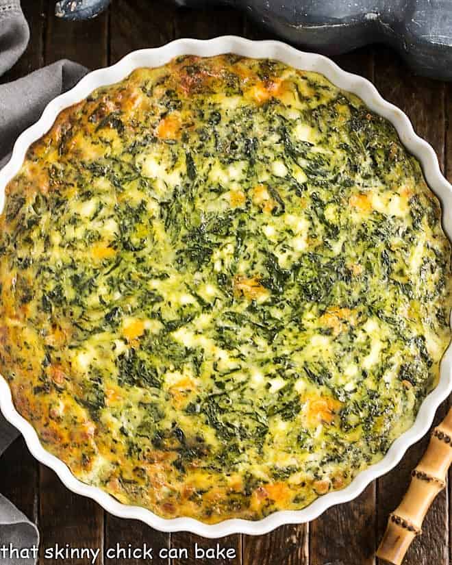 Overhead view of a spinach casserole in a round white ceramic baking dish.