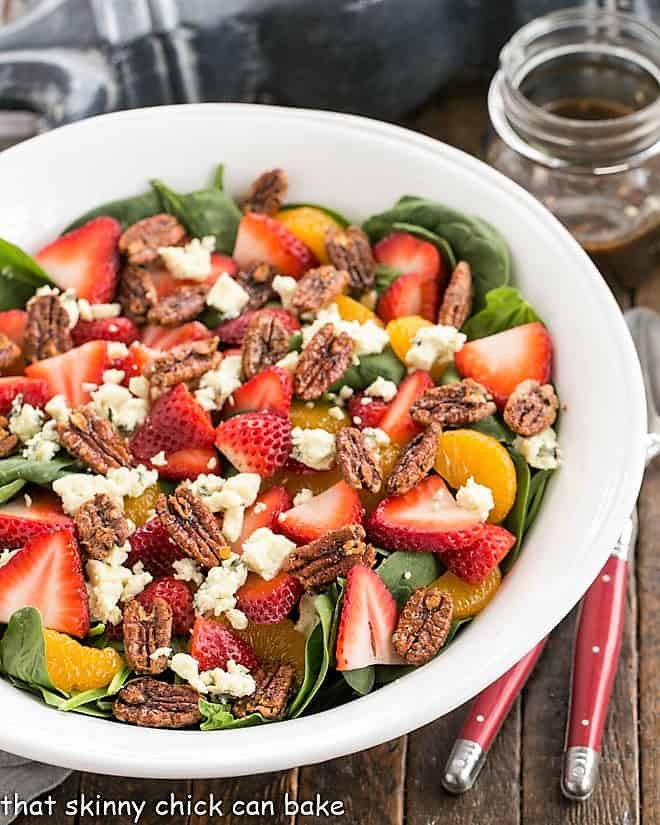 Overhead view of strawberry spinach salad with blue cheese in a white serving bowl.