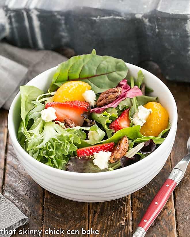 Overhead view of strawberry spinach salad in a white serving bowl.