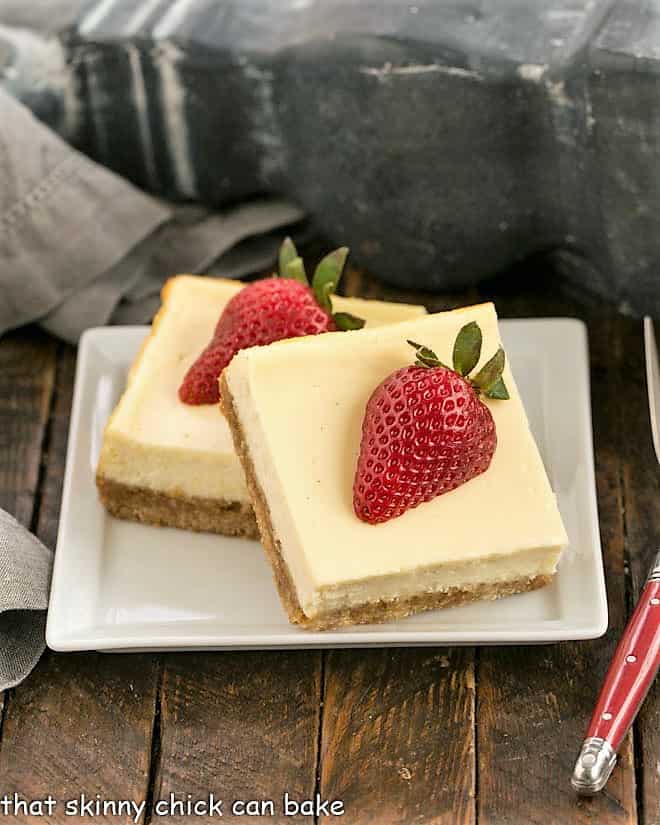 Overhead view of two vanilla bean cheesecae bars topped with strawberry halves