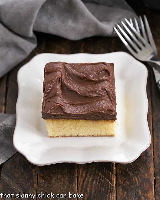 Overhead shot of a square of yellow snack cake on a square white dessert plate