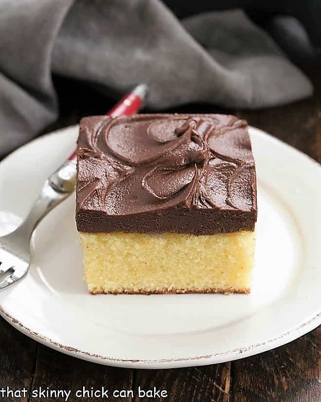 Yellow snack cake slice on a white plate with a red handle fork