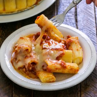 Baked rigatoni on a plate with a fork lifting up a noodle