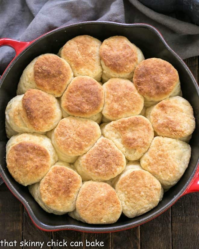 Overhead view of baked angel biscuits in a red cast iron skillet