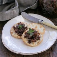 Bacon jam on crackers on a white appetizer plate