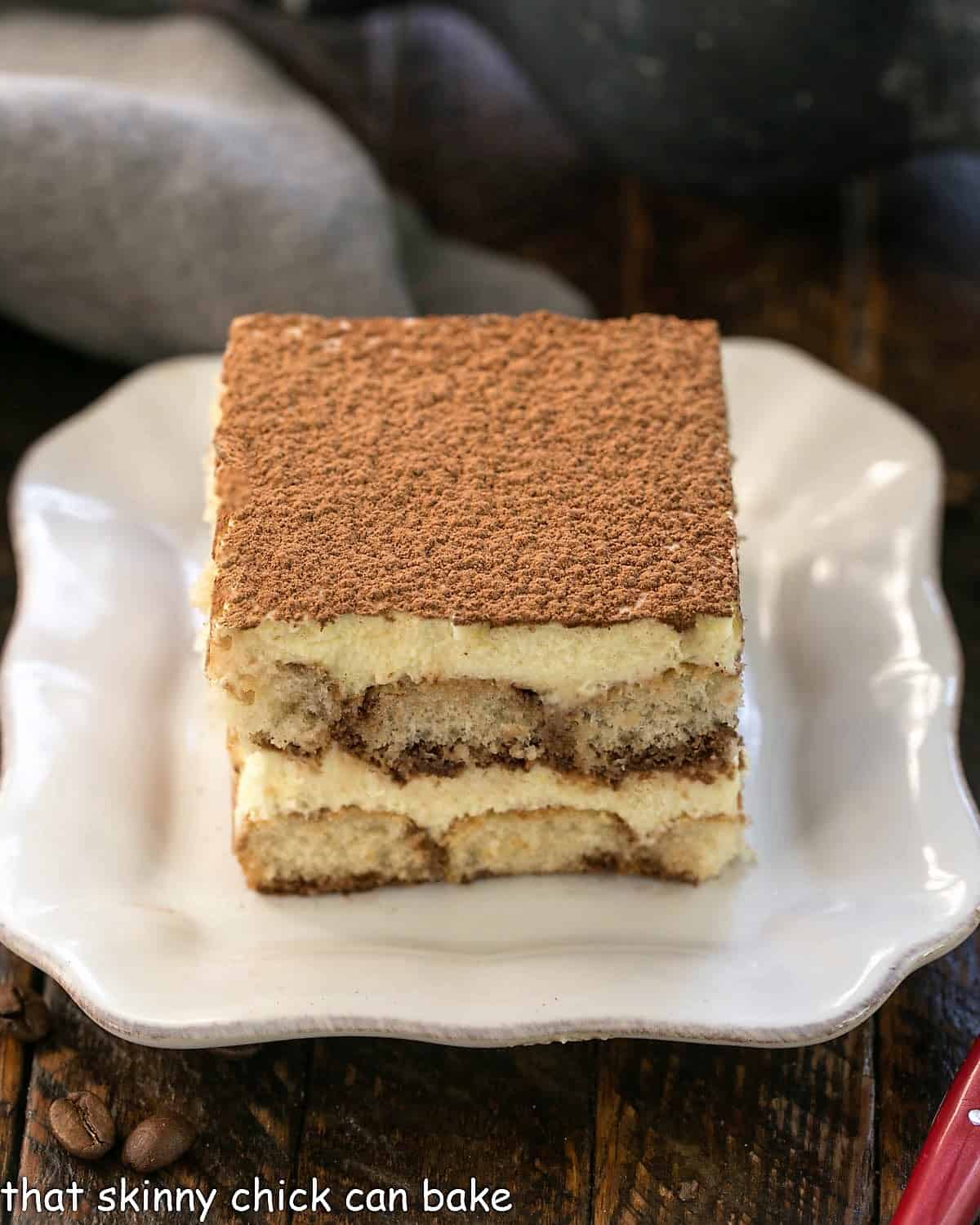 A slice of tiramisu on a square white plate.