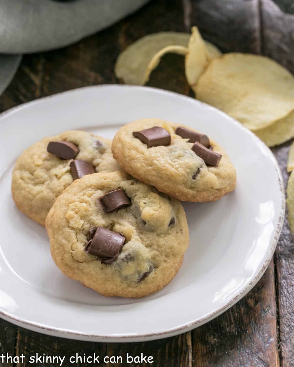 3 potato chip cookies on a white plate with chips in the background