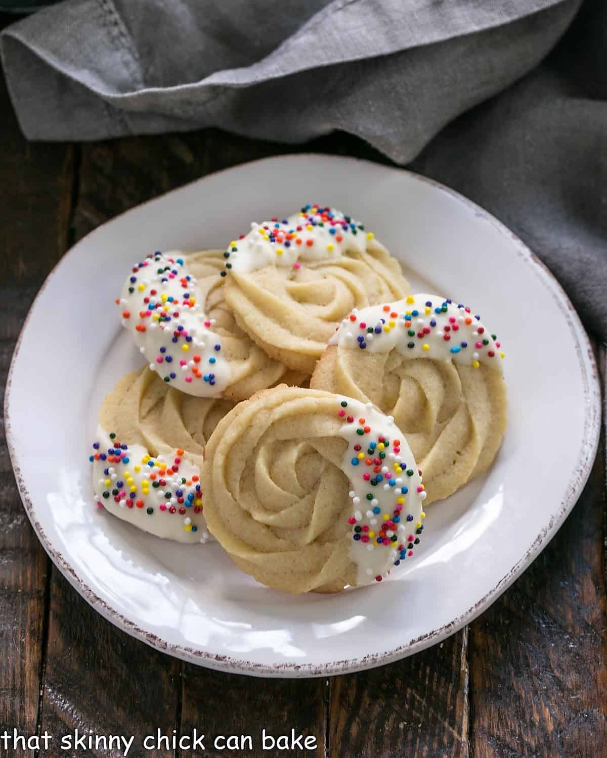 Overhead view of white chocolate dipped Danish butter cookies on a round white plate.