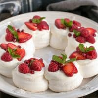 Christmas Pavlova on a white plate topped with red berries and mint