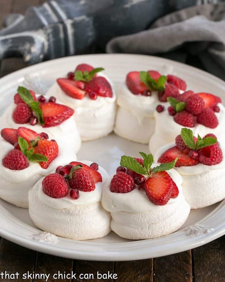 Christmas Pavlova on a white plate topped with red berries and mint