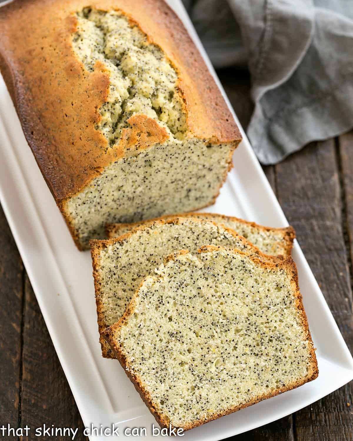 Sliced lemon poppy seed loaf on a white ceramic tray.